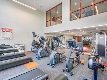 A gym with a variety of exercise equipment including treadmills, stationary bikes, and weight machines.